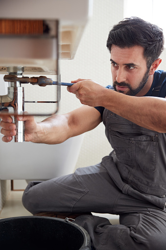 A plumber fixing the bathroom sink